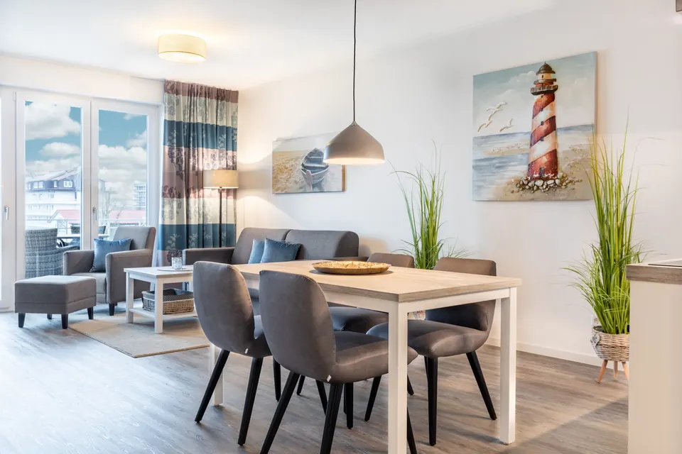 Wohnbereich mit Sofa, Esstisch und Leuchtturm-Bild